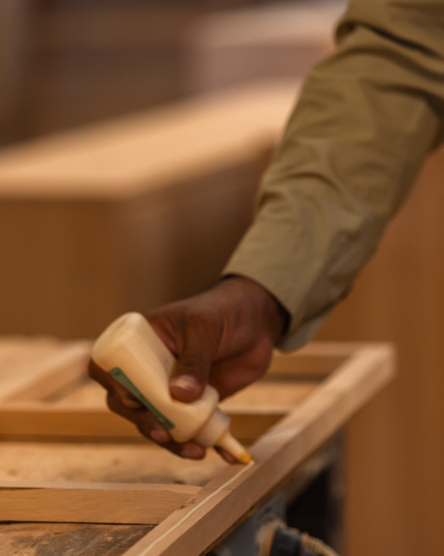 Hands gluing a solid-wood frame joint in the Cristo Rey Furniture workshop